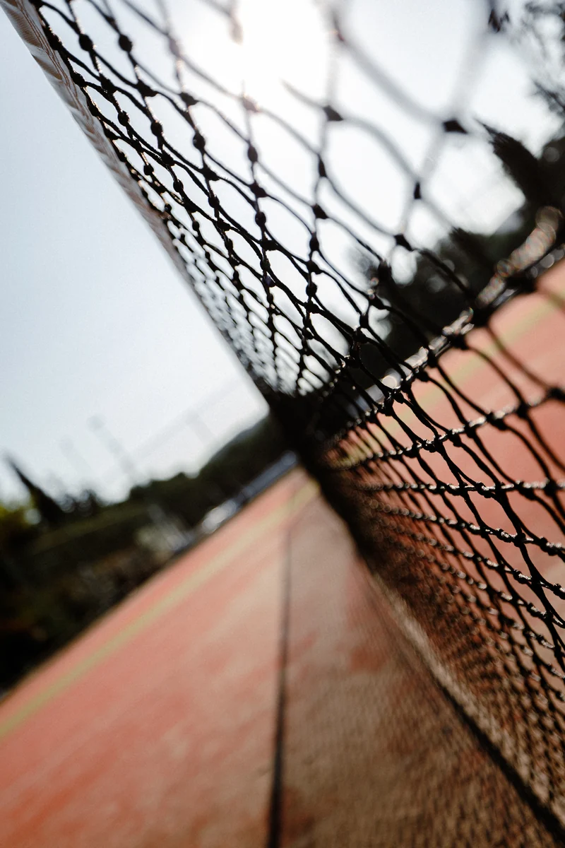 A close view along a tennis net in afternoon light